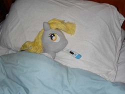 Size: 600x450 | Tagged: safe, artist:eratosofcyrene, derpy hooves, pegasus, pony, g4, bed, ear thermometer, female, irl, lying down, mare, on side, photo, pillow, plushie, sick, solo