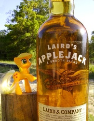 Size: 476x610 | Tagged: safe, artist:texasuberalles, applejack, earth pony, pony, g4, alcohol, applejack (drink), bottle, brushable, female, freckles, hatless, irl, laird & company, laird's applejack, looking up, mare, missing accessory, namesake, photo, pun, raised hoof, raised leg, smiling, solo, toy