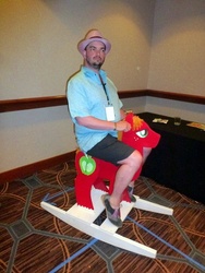 Size: 450x600 | Tagged: safe, big macintosh, human, g4, convention, craft, hat, horsepower, irl, irl human, peter new, photo, riding, rocking horse, trilby