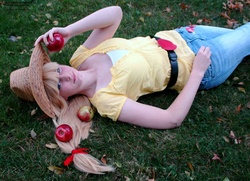 Size: 1600x1159 | Tagged: safe, artist:mickeydoo13, applejack, human, g4, apple, cosplay, grass, irl, irl human, obligatory apple, on back, photo, solo