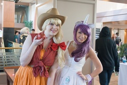 Size: 1080x720 | Tagged: safe, artist:kill3rsushi, applejack, rarity, human, g4, animation on display, apple, clothes, convention, cosplay, dress, ears, horn, irl, irl human, photo