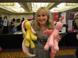 Size: 1024x768 | Tagged: safe, artist:nerdyknitterdesigns, fluttershy, pinkie pie, earth pony, human, pony, g4, andrea libman, convention, everfree northwest, everfree northwest 2013, female, irl, irl human, jewelry, knit, necklace, photo, plushie, smiling, voice actor, voice actor joke