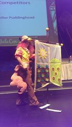 Size: 579x1024 | Tagged: artist needed, safe, chancellor puddinghead, pinkie pie, human, galacon, g4, hearth's warming eve (episode), 2014, convention, cosplay, defictionalization, flag, hanging banner, hearth's warming eve, irl, irl human, photo, stage