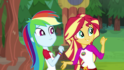 Size: 1280x720 | Tagged: safe, screencap, rainbow dash, sunset shimmer, equestria girls, g4, my little pony equestria girls: legend of everfree, camp everfree outfits, clothes, duo, female, pointing, scenery, shorts, sun, tree, wristband