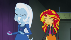 Size: 1280x714 | Tagged: safe, screencap, sunset shimmer, trixie, equestria girls, g4, my little pony equestria girls: rainbow rocks, clothes, eyes closed, fall formal outfits, grin, jacket, leather jacket, sad, smiling