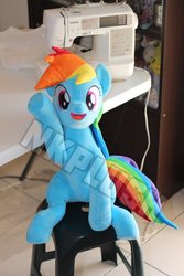 Size: 800x1200 | Tagged: safe, artist:nekokevin, rainbow dash, pegasus, pony, g4, cute, dashabetes, female, irl, looking at you, mare, open mouth, photo, plushie, raised hoof, sewing machine, smiling, solo, table, underhoof, watermark, waving
