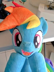 Size: 768x1024 | Tagged: safe, artist:nekokevin, rainbow dash, pegasus, pony, g4, cute, dashabetes, female, irl, looking at you, mare, open mouth, photo, plushie, raised hoof, sewing machine, smiling, solo, table, underhoof