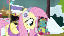 Size: 800x450 | Tagged: safe, screencap, fluttershy, holly the hearths warmer doll, pegasus, pony, g4, my little pony best gift ever, animated, clothes, earmuffs, female, mare, solo, sweater, winter outfit