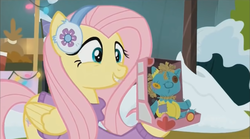 Size: 1352x754 | Tagged: safe, screencap, fluttershy, holly the hearths warmer doll, pegasus, pony, best gift ever, g4, clothes, cute, earmuffs, female, happy, mare, shyabetes, smiling, solo, sweater, winter, winter outfit