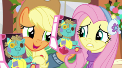 Size: 1280x720 | Tagged: safe, screencap, applejack, fluttershy, holly the hearths warmer doll, g4, my little pony best gift ever, clothes, duo, earmuffs, winter outfit, yay
