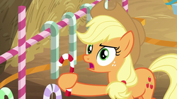 Size: 1280x720 | Tagged: safe, screencap, applejack, earth pony, pony, g4, the great escape room, candy, candy cane, female, food, freckles, hay, holding, mare, solo