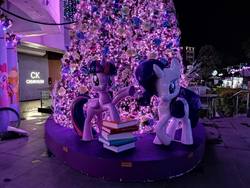Size: 960x720 | Tagged: safe, photographer:hongkoon, rarity, twilight sparkle, alicorn, pony, g4, book, christmas, christmas tree, holiday, night, purple, singapore, statue, tree, twilight sparkle (alicorn)