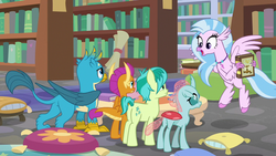Size: 1280x720 | Tagged: safe, screencap, gallus, ocellus, sandbar, silverstream, smolder, changedling, changeling, classical hippogriff, dragon, earth pony, griffon, hippogriff, pony, g4, what lies beneath, book, bookshelf, dragoness, female, library, male, pillow, scroll, teenager