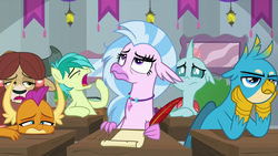 Size: 1280x720 | Tagged: safe, screencap, gallus, ocellus, sandbar, silverstream, smolder, yona, changedling, changeling, classical hippogriff, dragon, earth pony, griffon, hippogriff, pony, yak, g4, school daze, bags under eyes, bored, classroom, desk, displeased, floppy ears, male, paper, quill, quill pen, stallion, student six, yawn
