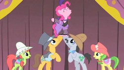 Size: 1280x720 | Tagged: safe, screencap, apple fritter, caramel, lucky clover, peachy sweet, pinkie pie, earth pony, pony, g4, over a barrel, apple family member, clothes, costume, dress, eyes closed, female, lifting, male, mare, puffy sleeves, saloon pinkie, singing, stage, stallion, you gotta share