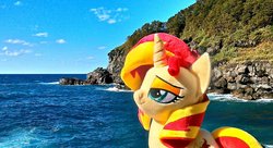 Size: 1199x651 | Tagged: safe, artist:nekokevin, sunset shimmer, pony, unicorn, g4, female, irl, mare, ocean, photo, plushie, rock, smiling, smug, solo