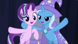 Size: 1667x939 | Tagged: safe, screencap, starlight glimmer, trixie, pony, unicorn, g4, road to friendship, bipedal, cape, clothes, cropped, cute, duo, female, glimmerbetes, hat, hind legs, hoof around neck, lidded eyes, mare, open mouth, smiling, trixie's cape, trixie's hat, waving