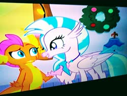 Size: 4160x3120 | Tagged: safe, screencap, silverstream, smolder, dragon, hippogriff, g4, the hearth's warming club, arms wide open, discovery family logo, duo, duo female, duo focus, female, hand up, hearth's warming eve, lamp, looking at each other, picture of a screen, raised eyebrow, shocked expression, smiling, wreath