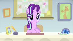 Size: 1280x720 | Tagged: safe, screencap, starlight glimmer, pony, unicorn, g4, interseason shorts, starlight the hypnotist, cute, desk, female, glimmerbetes, guidance counselor, hair flip, hair over one eye, mare, sitting, smiling, solo, starlight's office