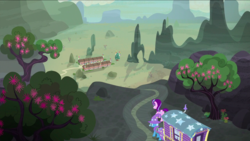 Size: 1440x810 | Tagged: safe, screencap, starlight glimmer, trixie, pony, unicorn, g4, to where and back again, desert, duo, female, flower, hat, mare, our town, scenery, tree, trixie's wagon, village, wizard hat