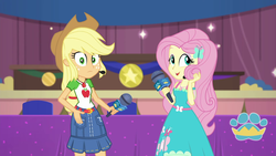 Size: 1920x1080 | Tagged: safe, screencap, applejack, fluttershy, best in show: the victory lap, equestria girls, g4, my little pony equestria girls: better together, applejack's hat, clothes, cowboy hat, dress, female, geode of fauna, geode of super strength, hat, looking at you, magical geodes, microphone, playing with hair, skirt