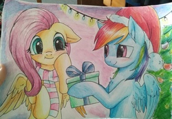 Size: 2560x1768 | Tagged: safe, artist:megabait, fluttershy, rainbow dash, pony, g4, blushing, christmas, christmas lights, christmas tree, clothes, female, gift giving, hat, hearth's warming, holiday, hoof hold, present, santa hat, scarf, ship:flutterdash, shipping, smiling, traditional art, tree