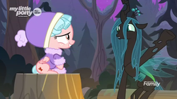 Size: 1366x768 | Tagged: safe, screencap, cozy glow, queen chrysalis, changeling, changeling queen, pegasus, pony, frenemies (episode), g4, clothes, cute, cutealis, discovery family logo, duo, female, filly, foal, forest, happy, hat, night, raised hoof, sitting, tree stump, winter outfit