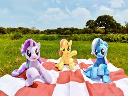 Size: 1024x768 | Tagged: safe, artist:nekokevin, starlight glimmer, sunset shimmer, trixie, pony, unicorn, series:nekokevin's glimmy, g4, cute, female, grass, irl, looking at you, magical trio, mare, nature, open mouth, photo, picnic, picnic blanket, plushie, raised hoof, river, sitting, sky, smiling, tree, trio, underhoof, water