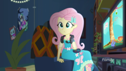 Size: 1600x900 | Tagged: safe, screencap, fluttershy, costume conundrum, equestria girls, g4, my little pony equestria girls: choose your own ending, controller, cute, female, gamershy, geode of fauna, headphones, magical geodes, poster, potted plant, shyabetes, sitting, sunset's apartment, television, video game