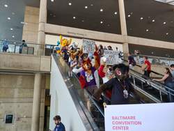 Size: 4656x3492 | Tagged: safe, artist:atalonthedeer, human, bronycon, bronycon 2019, baltimore convention center, bronies are diet furries, escalator, furry, fursuit, irl, irl human, photo