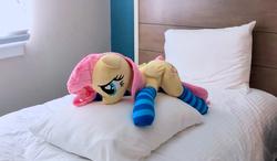 Size: 1280x746 | Tagged: safe, artist:dawning love, artist:natureshy, fluttershy, pony, g4, bed, clothes, heart eyes, irl, lying on bed, lying on pillows, photo, plushie, socks, solo, striped socks, wingding eyes