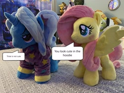 Size: 4032x3024 | Tagged: safe, artist:lumithekirin, fluttershy, trixie, pegasus, pony, unicorn, g4, alternate hairstyle, babysitter trixie, blatant lies, blushing, clothes, cute, diatrixes, dressup, duo, hoodie, i'm not cute, irl, photo, pigtails, plushie, shyabetes, speech bubble, spread wings, third person, wings