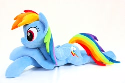 Size: 2048x1365 | Tagged: safe, artist:shunnkai, rainbow dash, pegasus, pony, g4, crossed arms, female, irl, lying down, mare, photo, plushie, prone, simple background, smiling, solo, white background