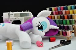 Size: 4096x2730 | Tagged: safe, artist:shunnkai, rarity, pony, unicorn, g4, fabric, female, irl, lidded eyes, looking at you, lying down, mare, photo, plushie, scissors, sewing machine, smiling, solo