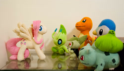 Size: 2880x1647 | Tagged: safe, artist:axure, fluttershy, axew, bulbasaur, celebi, charmander, pegasus, piplup, pony, g4, crossover, crowd, irl, looking back, mythical pokémon, photo, plushie, pokémon, spread wings, wings