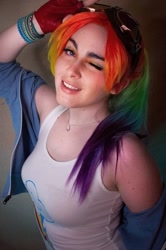 Size: 716x1080 | Tagged: safe, rainbow dash, human, g4, bracelet, clothes, cosplay, costume, cutie mark on clothes, goggles, irl, irl human, jewelry, looking at you, multicolored hair, one eye closed, photo, rainbow hair, tank top, wink, winking at you