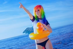 Size: 1080x722 | Tagged: safe, artist:natsumipon, rainbow dash, human, g4, beach, clothes, cosplay, costume, floaty, inflatable bird, inflatable duck, inner tube, irl, irl human, ocean, opaque inflatable, outdoors, photo, pointing, pool toy, seams, standing, swimsuit, water, wearing a swim ring, wrinkles