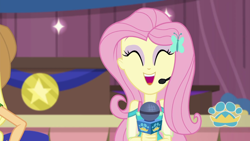 Size: 1280x720 | Tagged: safe, screencap, applejack, fluttershy, best in show: the victory lap, equestria girls, g4, my little pony equestria girls: better together, ^^, best in show logo, cute, eyes closed, hairpin, microphone, offscreen character, open mouth, shyabetes, smiling