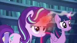 Size: 1000x562 | Tagged: safe, screencap, starlight glimmer, twilight sparkle, alicorn, pony, unicorn, every little thing she does, g4, duo, duo female, female, glowing horn, happy, horn, indoors, library, looking ahead, looking forward, looking up, magic, magic aura, overheated horn, smiling, smoke, twilight sparkle (alicorn), twilight's castle