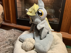 Size: 4032x3024 | Tagged: safe, artist:ciaran, derpy hooves, g4, bed, female, fireplace, food, grooming, irl, looking at you, muffin, photo, photography, plushie, preening, rug, welovefine
