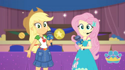 Size: 3410x1920 | Tagged: safe, screencap, applejack, fluttershy, best in show: the victory lap, equestria girls, g4, my little pony equestria girls: better together, applejack's hat, belt, best in show logo, clothes, cowboy hat, cutie mark, cutie mark on clothes, denim skirt, female, geode of fauna, geode of super strength, hairpin, hand on hip, hat, jewelry, magical geodes, microphone, necklace, skirt, smiling