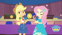 Size: 3410x1920 | Tagged: safe, screencap, applejack, fluttershy, best in show: the victory lap, equestria girls, g4, my little pony equestria girls: better together, applejack's hat, belt, best in show logo, clothes, cowboy hat, cutie mark, cutie mark on clothes, denim skirt, eyes closed, female, geode of fauna, geode of super strength, hairpin, hat, jewelry, magical geodes, microphone, necklace, skirt, smiling