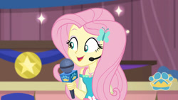 Size: 3410x1920 | Tagged: safe, screencap, fluttershy, best in show: the victory lap, equestria girls, g4, my little pony equestria girls: better together, best in show logo, female, geode of fauna, hairpin, jewelry, magical geodes, microphone, necklace, open mouth, smiling, solo