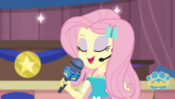 Size: 3410x1920 | Tagged: safe, screencap, fluttershy, best in show: the victory lap, equestria girls, g4, my little pony equestria girls: better together, best in show logo, eyes closed, female, geode of fauna, hairpin, jewelry, magical geodes, microphone, necklace, open mouth, solo