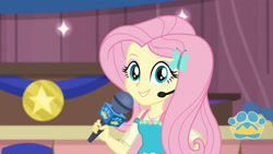 Size: 3410x1920 | Tagged: safe, screencap, fluttershy, best in show: the victory lap, equestria girls, g4, my little pony equestria girls: better together, best in show logo, female, geode of fauna, hairpin, jewelry, magical geodes, microphone, necklace, smiling, solo