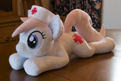Size: 5184x3456 | Tagged: safe, artist:azgchip, nurse redheart, earth pony, pony, g4, cute, female, hat, irl, lying down, mare, nurse hat, photo, plushie, pony plushie, prone, solo, sploot, table