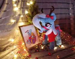 Size: 1949x1536 | Tagged: safe, artist:doctorkoda, artist:jewellier, photographer:jewellier, trixie, deer, deer pony, original species, pony, unicorn, g4, antlers, bell, cape, chocolate, christmas, christmas lights, christmas outfit, christmas tree, clothes, food, holiday, irl, photo, photo frame, plushie, reindeer antlers, ribbon, tinsel, traditional art, tree