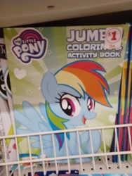 Size: 3000x4000 | Tagged: safe, rainbow dash, pegasus, pony, g4, coloring book, dollar tree, family dollar, female, high res, irl, mare, my little pony jumbo coloring book, my little pony logo, open mouth, open smile, photo, price tag, raised hoof, smiling, solo, spread wings, sticker, wings