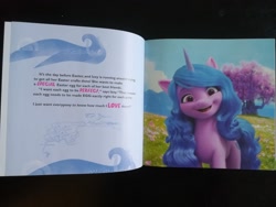 Size: 2048x1536 | Tagged: safe, izzy moonbow, pony, unicorn, g5, my little pony: a new generation, book, easter egg surprise, irl, photo, solo, text