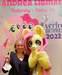 Size: 1080x1296 | Tagged: safe, artist:limeythecheetah, fluttershy, pinkie pie, human, pony, g4, andrea libman, everfree northwest, everfree northwest 2022, fursuit, irl, irl human, peace sign, photo, voice actor
